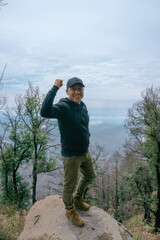 Happy Hispanic male standing on a rock during a hiking trail to El Pinal mountain in Puebla, Mexico