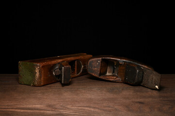 zwei alte dunkel braune antike holzhobel mit holzspan vor schwarzem hintergrund handwerk hobby