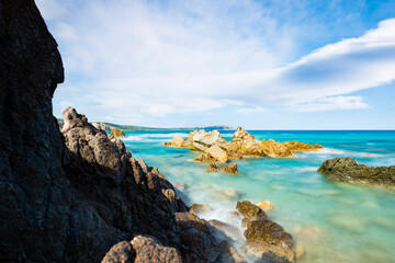 (Long exposure) Stunning view of a rocky coastline bathed by a turquoise, clear sea during a sunny, summer day, Rena Majore, Sardinia, Italy.
