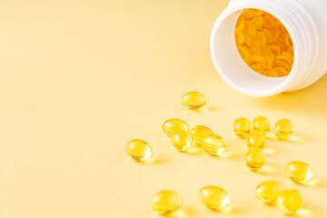 Fish oil soft gel supplement capsules source of omega 3 and vitamins A, E on yellow background near...