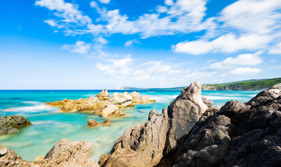 (Long exposure) Stunning view of a rocky coastline bathed by a turquoise, clear sea during a sunny, summer day, Rena Majore, Sardinia, Italy.