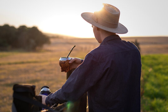 Ga&uacute;cho segurando chimarr&atilde;o p&ocirc;r do sol no pampa