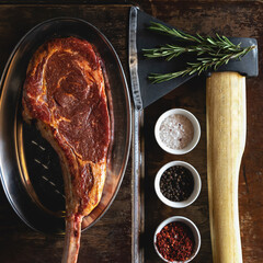 Flat lay, Tomahawk or t-bone steak, cooking process. Butcher ax for cutting meat, large piece of...