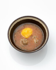 Fatty tomato soup with meatballs. Bowl of rich broth isolated on white background. Vertical format.