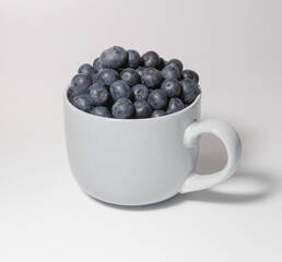 Blueberries in a large cup bowl on a white background. Close-up
