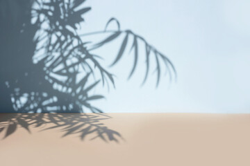 Palm leaves shadow on blue wall background and beige pastel floor. Summer tropical beach...