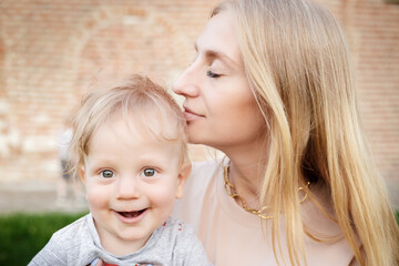 portrait of young mom with blond baby outdoors. Happy family. Mum with baby.