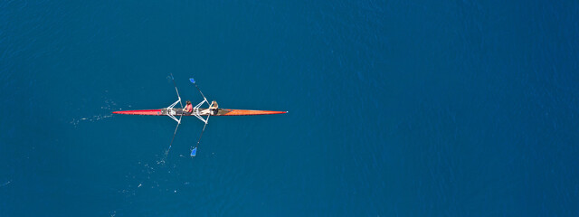 Aerial drone top ultra wide panoramic view of sport canoe rowing synchronous male athletes competing in deep blue sea - obrazy, fototapety, plakaty