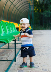 Portrait of a cheerful boy on a summer day. Beautiful child in a baseball cap at the stadium near the bright seats.