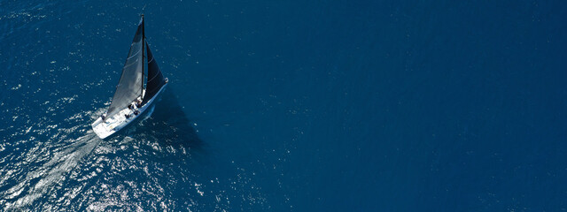 Aerial drone top down ultra wide photo of luxury sail boat cruising in the Aegean deep blue sea 