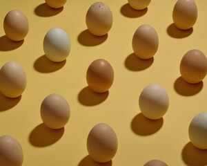 Rows of brown and white eggs on a yellow background.