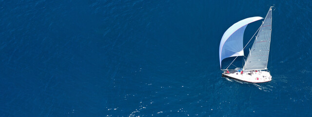 Aerial drone top down ultra wide photo of luxury sail boat cruising in the Aegean deep blue sea 