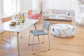 very light baroque style luxury interior of big sitting room. White walls decorated with awesome stucco. Royal style apartment with chic furniture with gold elements