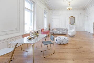 very light baroque style luxury interior of big sitting room. White walls decorated with awesome stucco. Royal style apartment with chic furniture with gold elements