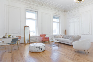 very light baroque style luxury interior of big sitting room. White walls decorated with awesome stucco. Royal style apartment with chic furniture with gold elements
