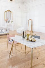 very light baroque style luxury interior of big sitting room. White walls decorated with awesome stucco. Royal style apartment with chic furniture with gold elements