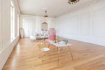 very light baroque style luxury interior of big sitting room. White walls decorated with awesome stucco. Royal style apartment with chic furniture with gold elements