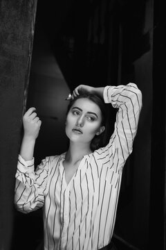 Black and white indoor portrait of a sad glamorous young woman wears striped white shirt