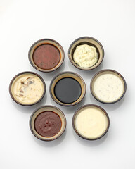 Sauces in clay pots isolated on white background. Different types of sauces, mayonnaise, mustard, soy sauce, ketchup. Flat lay.