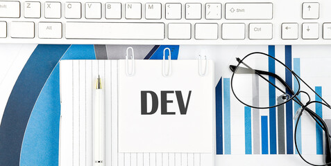 Office desk table with keyboard, chart,glasses and pen. Top view with text DEV