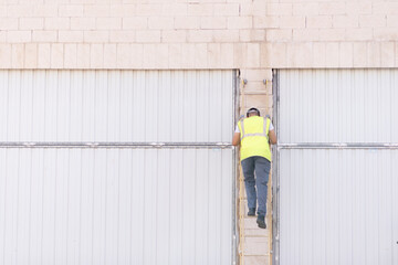 telecommunications technician on his back on a ladder working on the facade of a building. 
