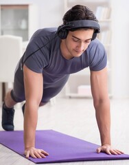 Fototapeta premium Man doing sports at home and listening to music