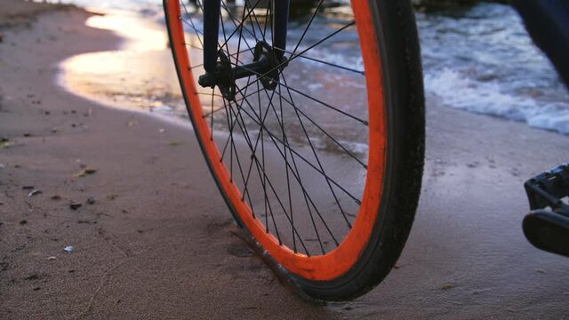 City Single Speed Fixed Gear Bike Wheel Standing on the Beach Sand Hit by Calm Sea Waves