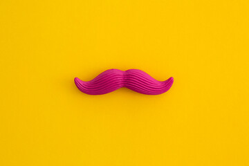Pink mustache on yellow background. Top view with copy space. Flat lay.