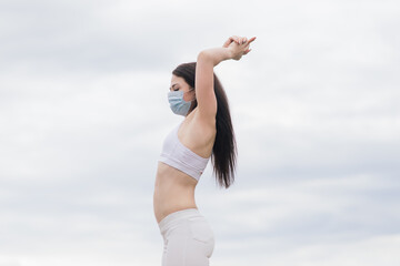 Fototapeta na wymiar Sport during quarantine, coronavirus, covid-19. Young athletic woman wearing medical protective mask