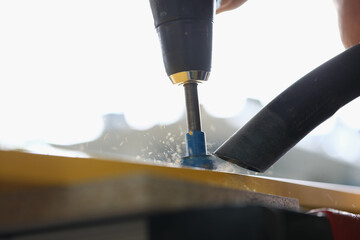 Close-up of foreman drilling hole in yellow wooden plank