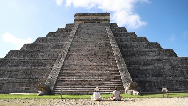 Two people meditate near the Mayan pyramid in Chichen Itza