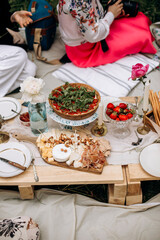 outdoor party with pie and cheese plate. summer picnic and pallet table with food and snacks. quiche pie with tomatoes and herbs and a cheese plate.