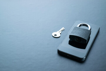 Internet protection. Modern space grey mobile phone with padlock, key on dark background. Darkweb, darknet and hacking concept.