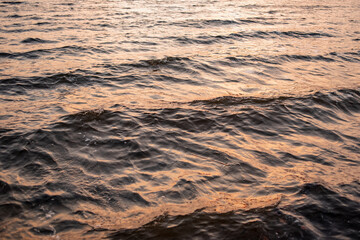 picture of the surface water in the sunset time. The texture of the river water at sunset.