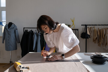 Tailor work with cloth in atelier. Young woman designer measure material with plastic ruler on...