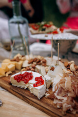 brie cheese with red currant jam. camembert cheese with red jam. cheese plate with prosciutto or dried ham close-up.