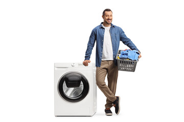 Casual young guy with a laundry basket and a washing machine