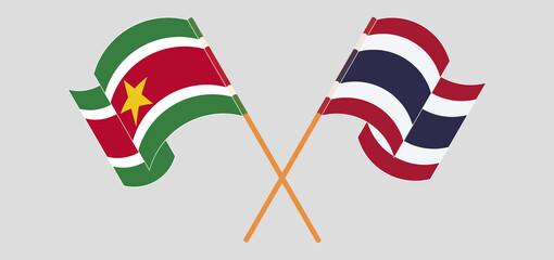 Crossed and waving flags of Suriname and Thailand