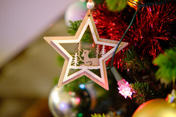 A star-shaped wooden Christmas tree decoration with a lamb and conifers.