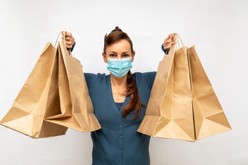 mulher usando máscara protetora azul carregando várias sacolas de compras com as duas mãos em...