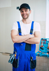 Professional young repairman in worker uniform and cap with modern toolbox with equipment after...