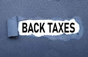 Back Taxes.text on torn cardboard. black letters on white paper