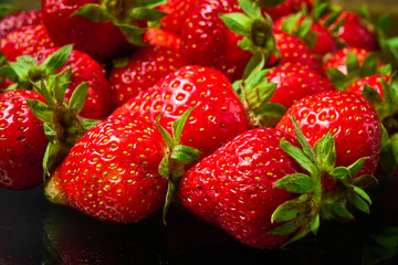 Ripe red strawberry on a black background, close-up.