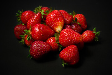 A slide of ripe red strawberries on a black background, close up.