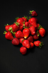 A slide of ripe red strawberries on a black background, close up.