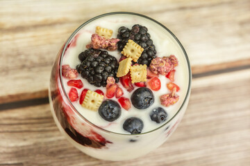 Close-up of a healthy yogurt with pomegranate stones, blackberries, bilberries and muesli