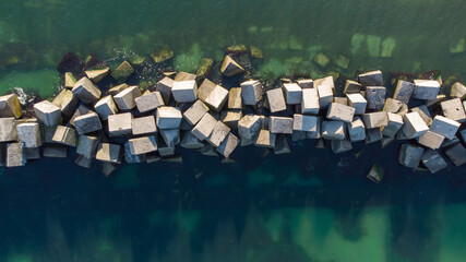 A breakwater made of white concrete cubes and a leading sign at the entrance to the port of Yuzhny....