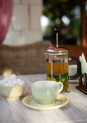Cup of tea, teapot, vase, sugar on the table in the cafe