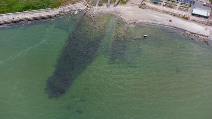 Seashore in an industrial area. Waste water discharge pipes into the sea. Aerial view.
