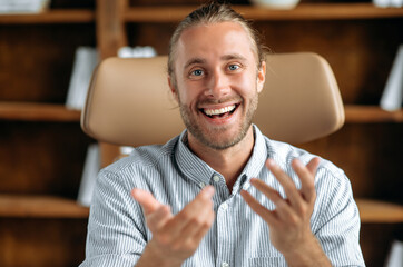 Friendly smart confident caucasian businessman or tutor, communicating with colleagues or client on conference call, looking at camera, gesturing with his hands, smiles pleasantly